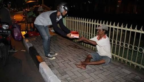 Seorang pemuda membagikan nasi kotak saat sahur on the road. - bincangsyariah.com
