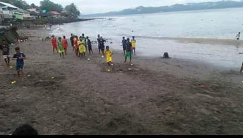 Anak anak bermain bola di dekat pantai