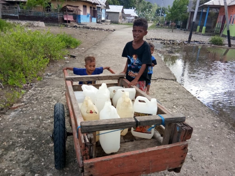Seorang Anak Desa Salagur Sedang Mendorong Gerobak Berisikan Cergengan Air Bersih