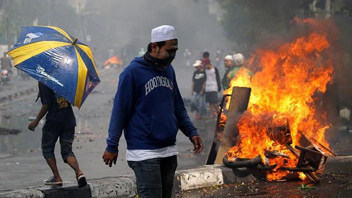 Seorang pria berjalan melewati ban yang terbakar dalam kerusuhan 22 Mei di Jakarta, Rabu, 22 Mei 2019. Sampai saat ini, aparat dibantu masyarakat masih bersiaga di lokasi tempat terjadinya kericuhan. REUTERS/Willy Kurniawan