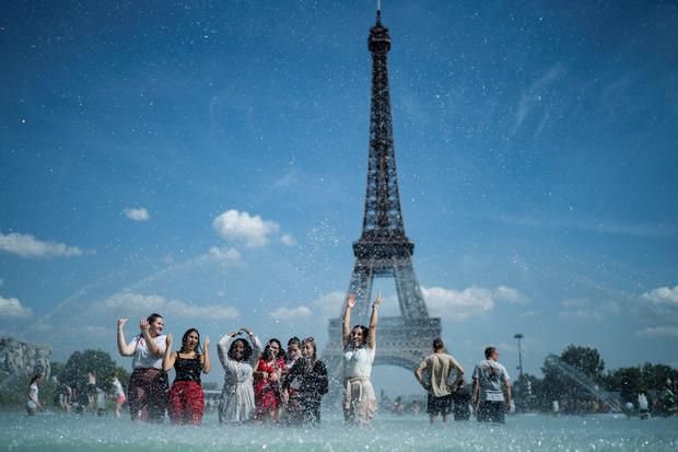 Sekelompok warga menikmati sejuknya air di kolam air dekat menara Eiffel (sumber: e-News.us / Getty Images)