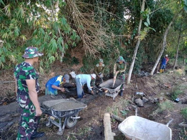 Personel TNI bersama Masyarakat saat Mengerjakan Pembuatan tanggul Penahan Tanah (Foto : Pendim 0815 Mjk)