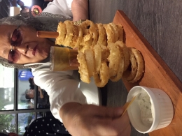 Eyang Uti, nenekku, mengambil saus krim asam dari hidangan cincin bawang goreng dengan sepotong keripik Nachos