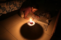 sumber:Seorang anak kecil di Bekasi belajar mengunakan lilin saat listrik padam se-Jabodetabek. katadata.com)
