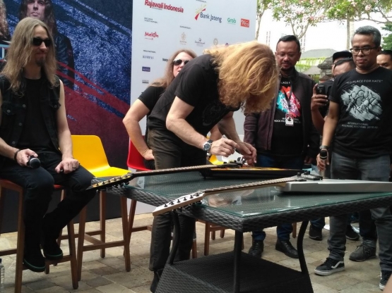 Dave Mustaine tengah membubuhkan tanda tangannya pada 2 gitar yang akan dilelang untuk korban gempa Palu. Pada Oktober 2018, Megadeth tampil di depan publik Indonesia melaui Jogjarockarta yang digelar di Stadion Kridosono, Yogyakarta | Foto medcom.com