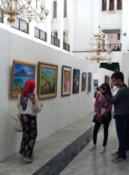 Beberapapengunjung  mengabadikan diridi depan lukisan para seniman yang dipamerkan (Sumber: J.Haryadi)