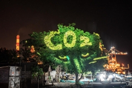 Ilustrasi yang diproyeksikan ke sebuah pohon dengan latar belakang PLTU Celukan Bawang dalam acara Summer Festival 2.0 di Bali. (Foto: Greenpeace)