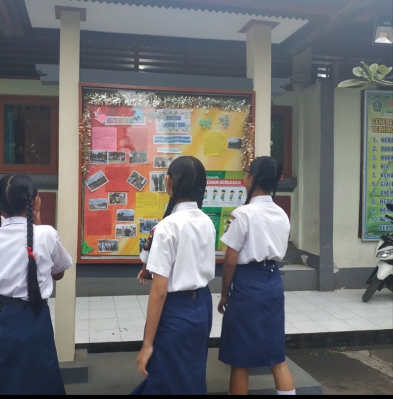 Siswa membaca mading yang dibuat oleh temannya yang tergabung dalam ekstrakurikuler jurnalistik