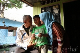 Kasran (kiri) bersama cucu dan istrinya menunujukkan Kartu Indonesia Sehat miliknya. (dokpri)