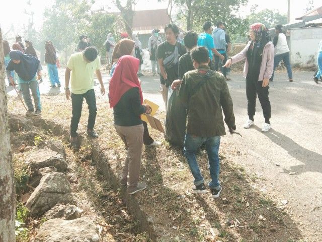 Ketua PKK Bantaeng (gaun pink) bersama murid SD membersihkan jalan desa dari sampah berserakan.