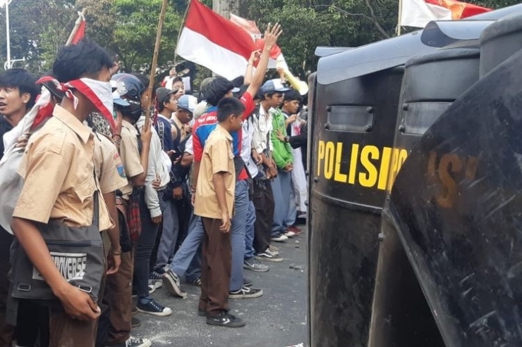 Ratusan pelajar dengan seragam pramuka, SMK, dan STM menyerang aparat kepolisian dari brimob yang sedang bertugas menjaga pintu belakang Gedung DPR/MPR RI, Jakarta Pusat. Pantuan Kompas.com pada Rabu (25/9/2019) siang, sekitar pukul 14.00 WIB, massa dari kalangan pelajar sempat melempari batu ke arah aparat yang sedang bertugas.(KOMPAS.com/BONFILIO MAHENDRA WAHANAPUTRA LADJAR) 