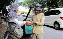 Seorang Perempuan Membantu Kakek Tua.  Foto diambil dari klikmu.co