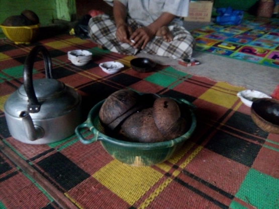 Tuan rumah sedang menunggu kedatangan teman sehobinya. Di hadapannya telah tersedia beberapa buah sayak dan sebuah cerek berisi air kopi daun. Dari tiga komunitas yang saya kunjungi, hanya di sinilah yang masih menggunakan sayak sebagai cangkir minumnya. Dokumentasi pribadi.