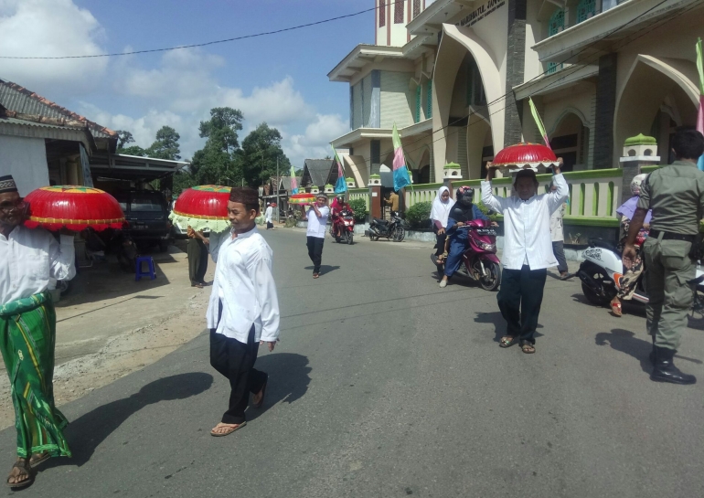 Lelaki membawa dulang berisikan berbagai penganan dalam adat Nganggung, dilakukan warga di Bangka dalam perayaan Maulid (dokpri) 