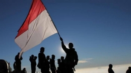 Salah seorang Pemuda Indonesia menggenggam Bendera Merah Putih di Puncak Gunung.