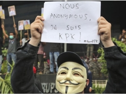 A masked supporter of Indonesian Corruption Eradication Commission (KPK) holds up a poster declaring 