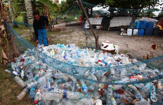 Seorang nelayan mengumpulkan botol dari untuk dijual. Pekerjaan memulung biasa dilakukan nelayan di Kepri untuk bertahan hidup saat tidak bisa melaut akibat cuaca buruk. Foto/Joko Sulistyo