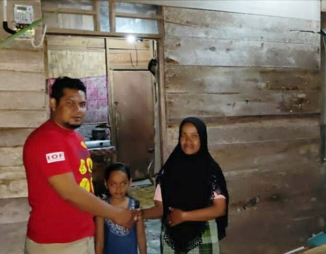 Agus Setiawan bersama Musryidah dan Nurasyiah di kediaman mereka, setelah arus listrik terpasang. (Foto/Istimewa).
