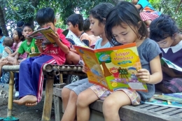 Salah satu anak di Dusun Tangga, Desa Selengen, Lombok Utara tampak membaca buku yang baru didapatnya.(KOMPAS.com/ Karnia Septia)