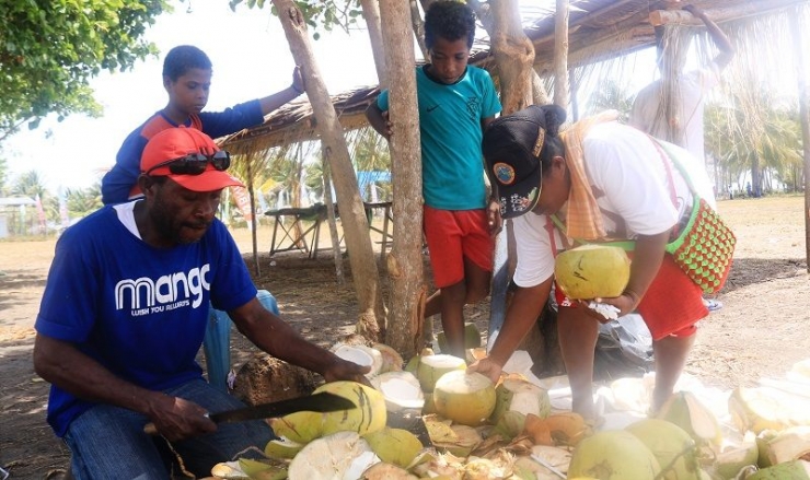 Rinus Urbasa (kiri) membela kelapa muda melayani pembeli pada Festival Suling Tambur Raja Ampat di Kampung Pam, Desember 2019 (Dokumentasi pribadi)