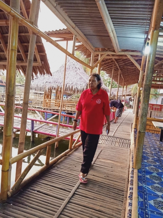 Ibu berjalan di atas jembatan bambu penghubung antar rumah. Photo by Ari