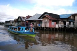 Sebuah perahu lain yang melintasi Sungai Martapura dengan latar belakang rumah tradisional Banjar (sumber foto: J.Haryadi)