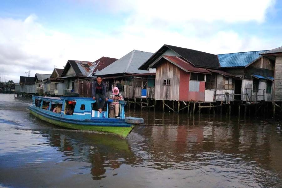 Sebuah perahu lain yang melintasi Sungai Martapura dengan latar belakang rumah tradisional Banjar (sumber foto: J.Haryadi)