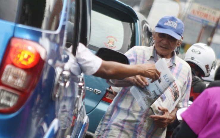 Seorang Loper Koran sedang menjajakan korannya kepada pengguna jalan raya. Foto: Istimewa (Ilustrasi dari Wartapilihan.com)
