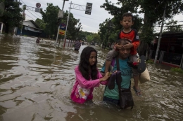 Warga yang tengah melewati banjir untuk mencari tempat perlindungan | Gambar: KOMPAS.com/M. Zaenuddin