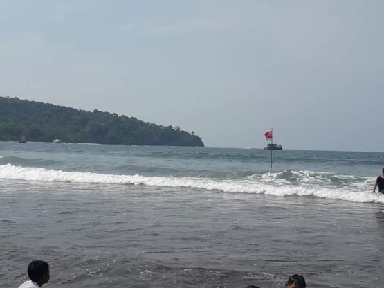 Bendera merah di laut tepi pantai yang merupakan tempat rawan arus deras. Photo by Ari