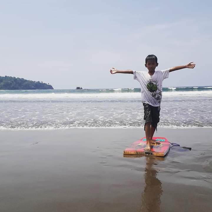 Bergaya di atas papan selancar di Pantai Pangandaran. Photo by Ari