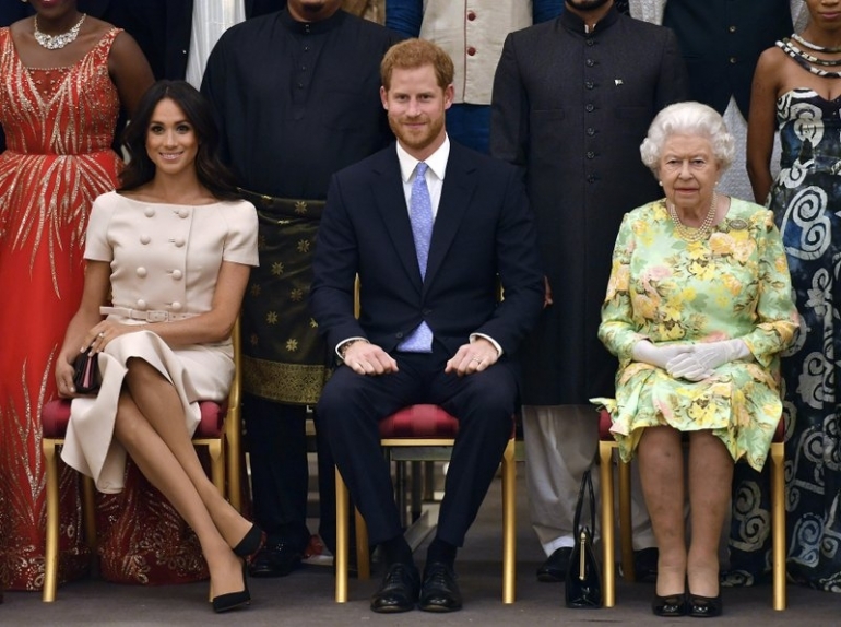 Britain's Queen Elizabeth, Prince Harry and Meghan, Duchess of Sussex pose for a group photo at the Queen's Young Leaders Awards Ceremony at Buckingham Palace in London (Tuesday, June 26, 2018). (Sumber: APnews/John Stillwell)