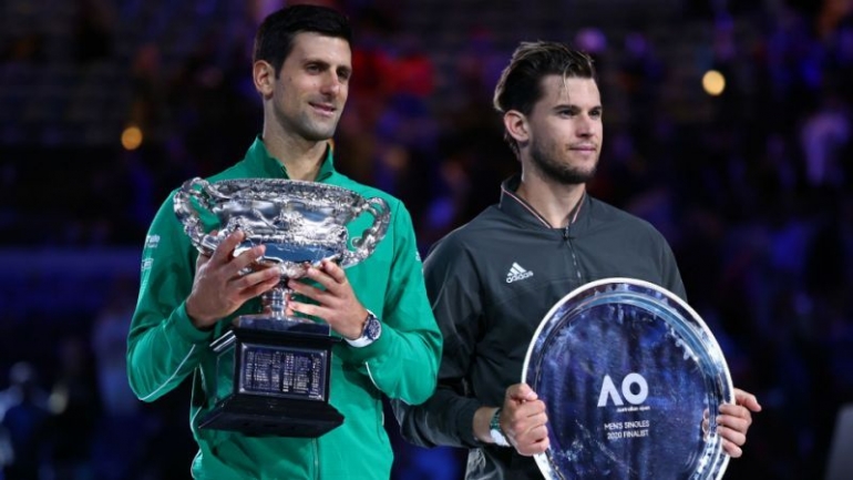 Novak Djokovic (kiri) dan Dominic Thiem memegang trofi juara dan finalis AO 2020. (sumber: foxsports.com)