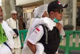 Seorang petugas haji tampak sedang menggendong jemaah haji lanjut usia / sumber foto: kemenag.go.id