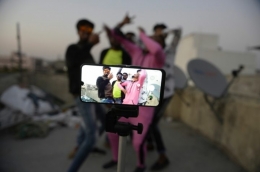 Para pemuda beraksi di depan kamera telepon seluler ketika membuat video TikTok di sebuah teras rumah keluarga mereka di Hyderabad, India, 14 Februari 2020 (NOAH SEELAM/AFP via KOMPAS.id)