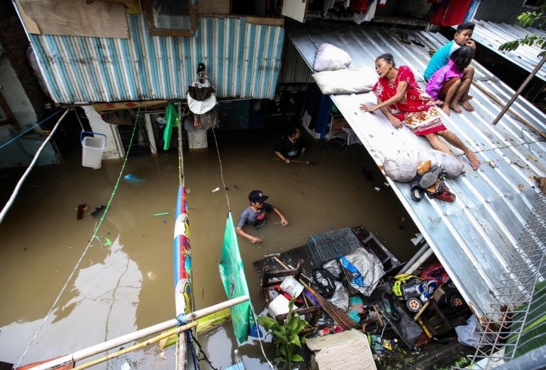 Warga menggunakan atap untuk berlindung sebelum di evakuasi saat banjir di Jalan Karet Pasar Baru, Karet Tengsin, Jakarta Pusat, Selasa (25/2/2020). Hujan deras sejak Senin dini hari membuat sejumlah daerah di Ibu Kota tergenang banjir. (KOMPAS.com/GARRY LOTULUNG)