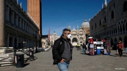 Pria bermasker yang berjalan di tengah alun-alun St. mark Venesia (Reuters)