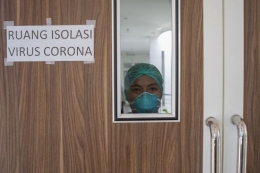 Seorang perawat Indonesia melihat melalui jendela kaca dari ruang isolasi untuk pasien yang terinfeksi virus corona, di Rumah Sakit Undata di Palu, Sulawesi Tengah, Indonesia, 3 Maret 2020. Rumah sakit di seluruh negeri sedang bersiap-siap untuk menghadapi kemungkinan wabah setelah dua kasus pertama virus corona. (Foto: EPA-EFE/OPAN BUSTAN)