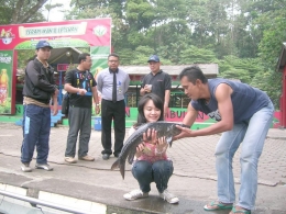 Seorang pawang membantu wisatawan memegang ikan dewa. | dokpri