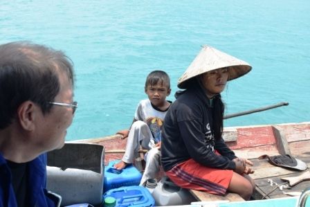 Dokter Lie A. Dharmawan menyapa Orang Suku Laut di perahu kajangnya. Sumber gambar: dokumen pribadi.