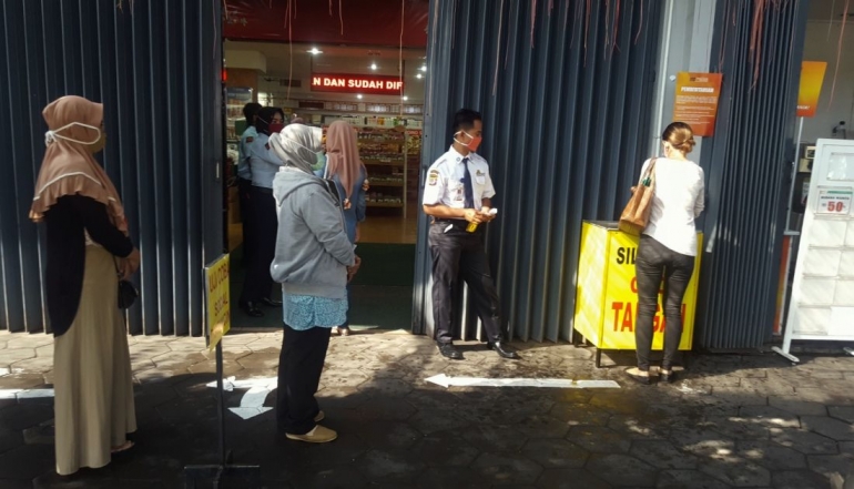 Petugas mengawasi antrean di depan pintu masuk Mirota Kampus C. Simanjuntak, Yogyakarta pada Rabu (25/3/2020) (dok. pri). 