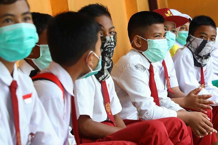 Siswa sekolah dasar di Natuna, Kepulauan Riau, mengenakan masker saat berada di area sekolah mereka, Selasa (4/2/2020). Hampir seluruh warga di Natuna menggunakan masker menyusul keputusan Pemerintah RI untuk menempatkan WNI yang dievakuasi dari Wuhan, China, di pulau tersebut.(AFP/RICKY PRAKOSO)
