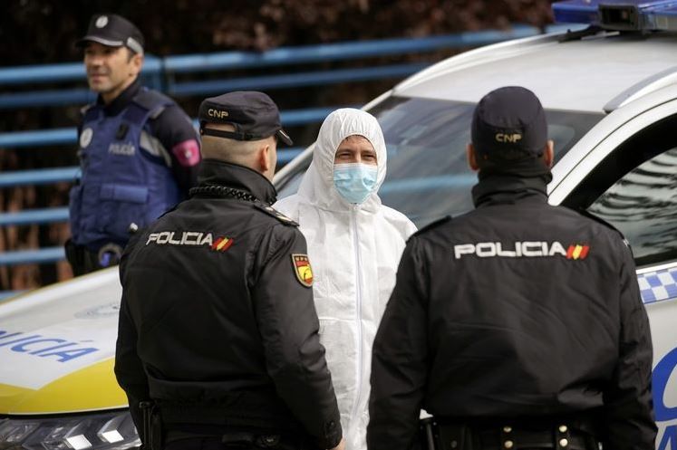 Seorang anggota dari militer Spanyol berbicara dengan dua polisi di Madrid, pada 24 Maret 2020, di tengah wabah virus corona.(REUTERS/JUAN MEDINA)
