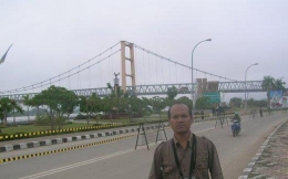 Berpose dengan latar belakang Jembatan Kuning Kutai Kartanegara.