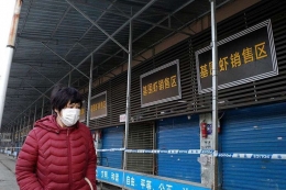 Seorang perempuan melintas di depan pasar Kota Wuhan Januari lalu. Foto afp/noel celis dipublikasikan kompas.com