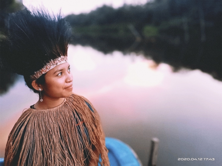 Gambar Ilustrasi, ketika Perempuan Memes Papua mengenakan pakaian adat: cawat yang berwarna coklat dan Habukhapio (hiasan kepala biasnya dari bulu burung).