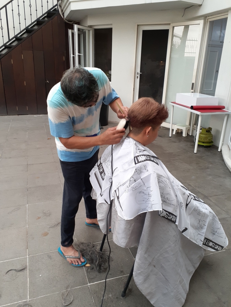 Ilustrasi tukang cukur rambut melakukan pemotongan rambut di sebuah rumah (Foto : Gideon Budiyanto)