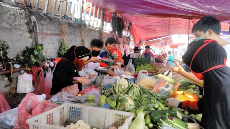 Tukang sayur-mayur dan pembelinya mengenakan masker wajah di Pasar Rakyat Pamulang, Kota Tangsel, Minggu pagi (19/04/2020). (Foto: Gapey Sandy)