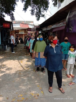 Para warga yang menganti untuk memperoleh makanan dan masker gratis dengan kepatuhan menjaga jarak