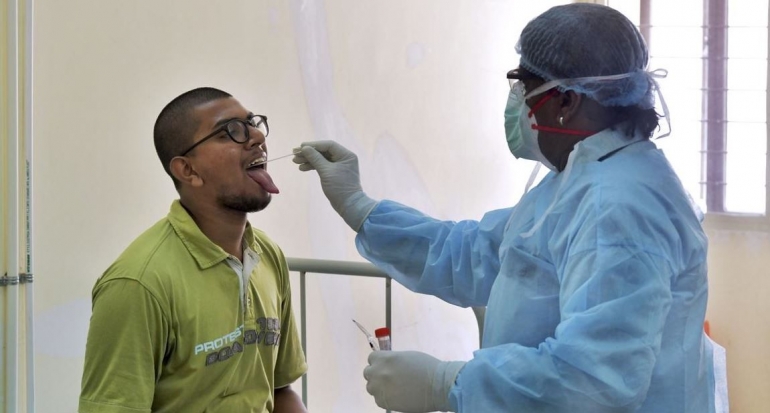 Seorang pekerja medis mengambil spesimen orofaring untuk mengumpulkan sampel untuk pengujian Covid-19 di Bengaluru, India. Foto : AFP